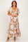 woman wearing a tan floral maxi dress with short flutter sleeves and a tie front detail
