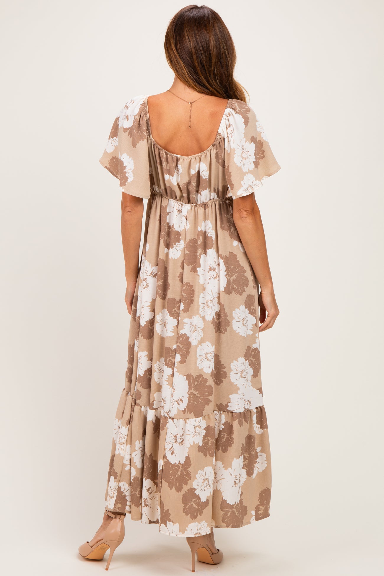 woman wearing a taupe floral print maxi dress with short flutter sleeves and a tiered skirt