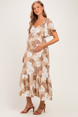 woman wearing a floral beige maternity dress with a tiered skirt and holding her baby bump
