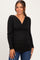 woman wearing a black long sleeve maternity top with a wrap design and gathered sides, smiling at the camera