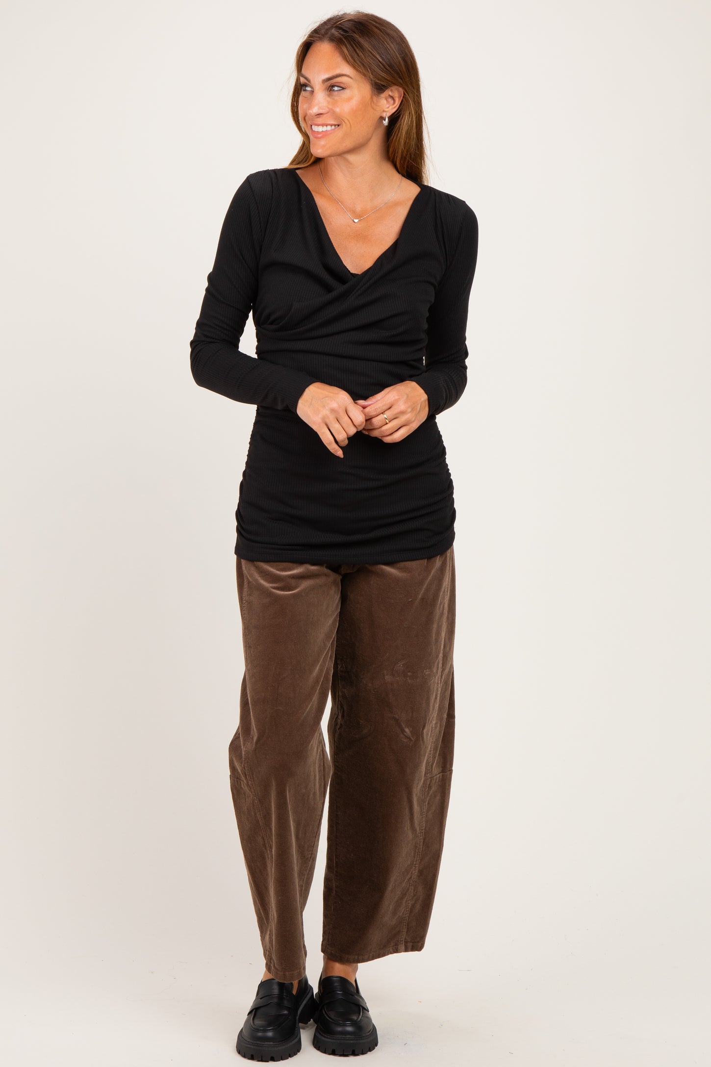 woman wearing a black long sleeve wrap top with ruching and brown wide-leg corduroy pants