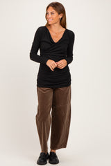 woman wearing a black long sleeve wrap top with ruching and brown wide-leg corduroy pants