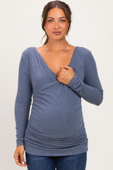 woman wearing a blue ribbed long sleeve maternity top that accentuates her baby bump