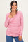 woman wearing a soft pink long sleeve wrap top with a ruched design and smiling at the camera