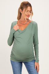 woman wearing a sage green long sleeve maternity top with a wrap design and a visible baby bump