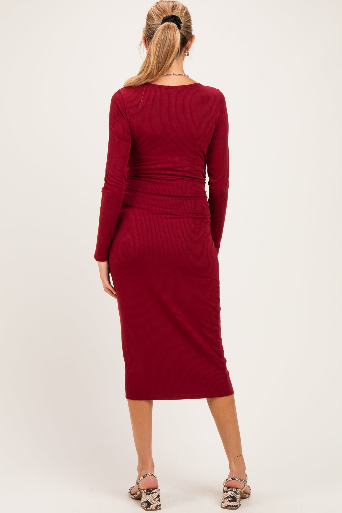 woman wearing a burgundy long sleeve maternity dress with a fitted silhouette, shown from the back