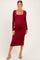 woman wearing a burgundy long sleeve maternity dress with a square neckline and fitted silhouette, showing her baby bump