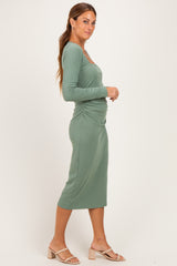 woman wearing a fitted sage green ribbed midi dress with ruching details and long sleeves