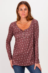 woman wearing a mauve long sleeve henley shirt with floral print and button detail, posing with hands on hips