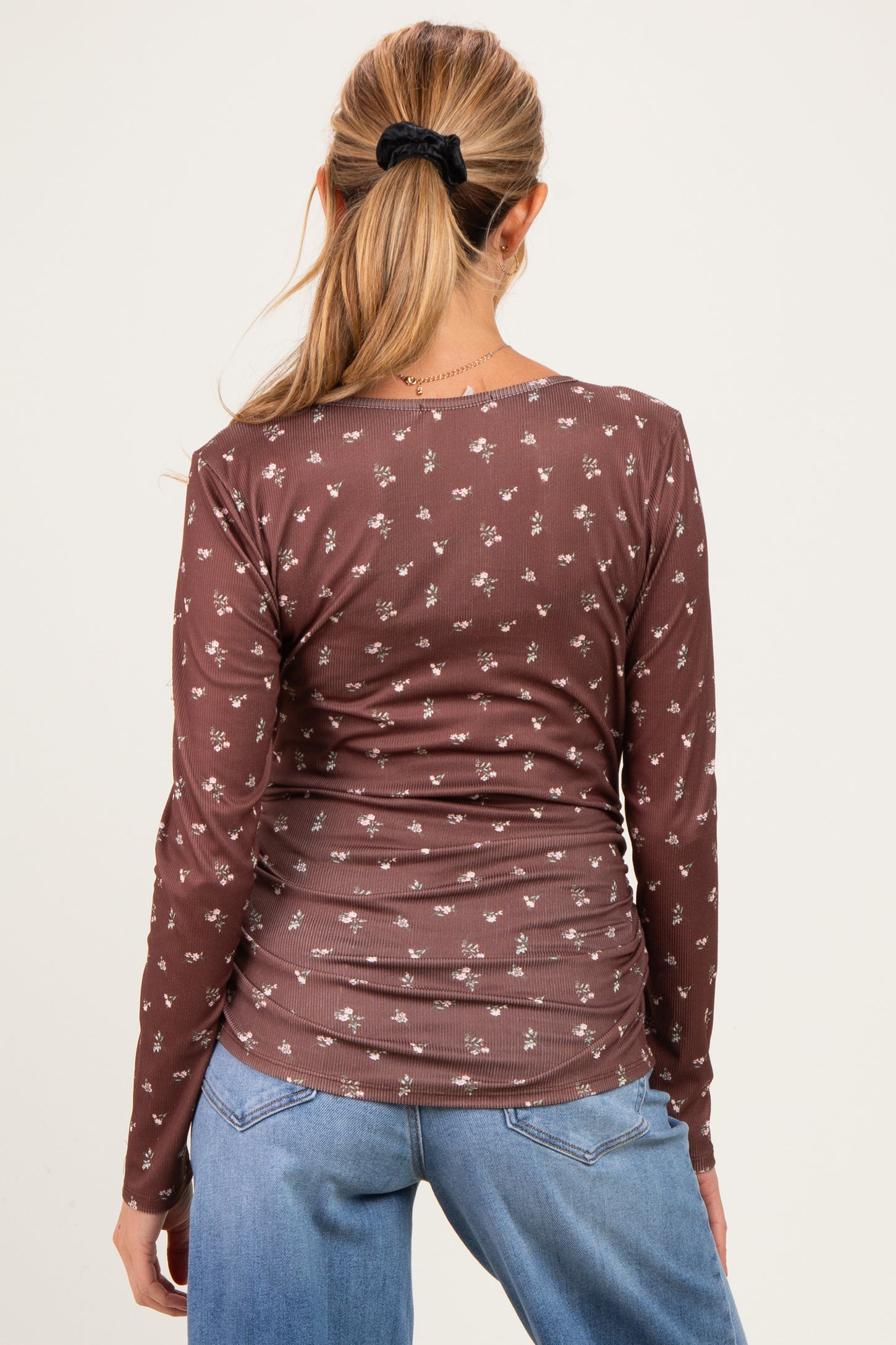 woman wearing a brown long sleeve maternity top with a floral print, showing the back view