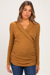 woman wearing a mustard ribbed maternity top with a wrap front and ruched sides, showing her baby bump