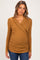 woman wearing a mustard ribbed maternity top with a wrap front and ruched sides, showing her baby bump