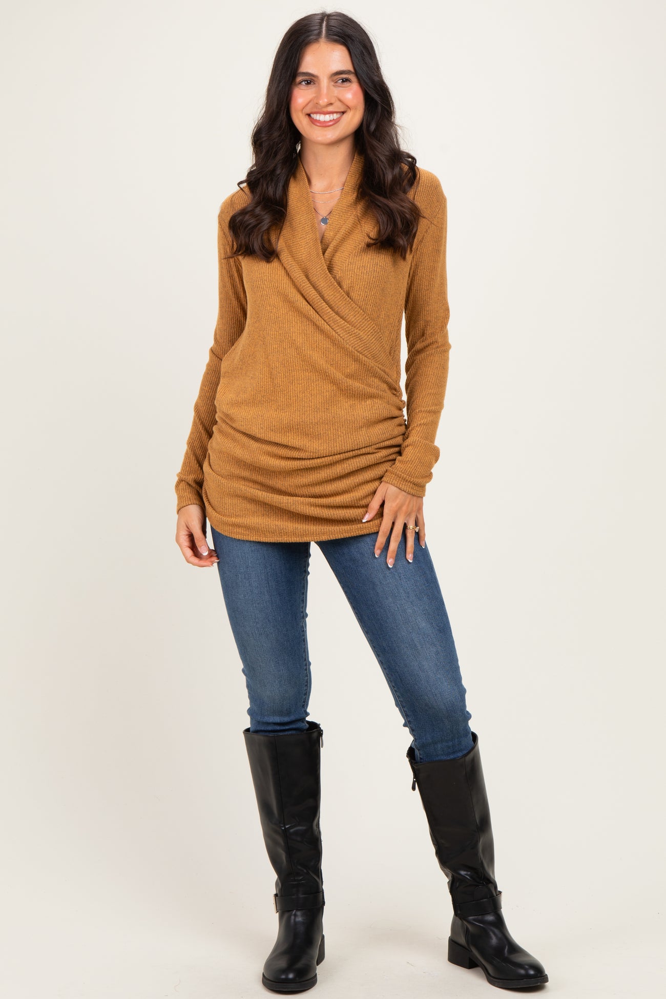 woman wearing a mustard yellow long sleeve wrap top with a fitted silhouette and jeans, paired with black knee-high boots