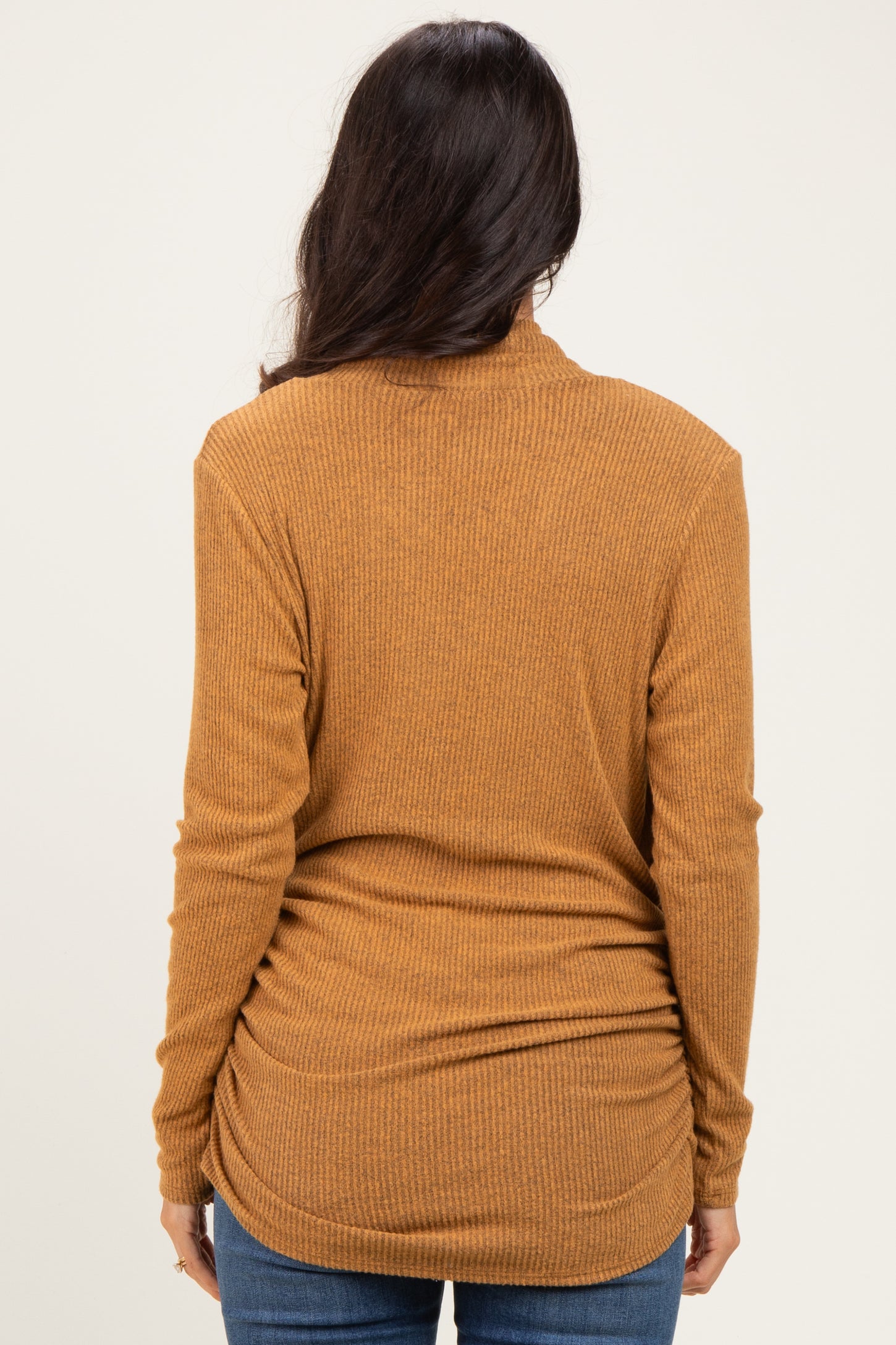 woman wearing a mustard yellow long sleeve ribbed top, viewed from the back