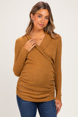 woman wearing a rust ribbed long sleeve maternity top with a crossover design and a visible baby bump