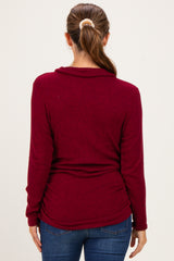 woman wearing a burgundy maternity top with a cowl neck and gathered sides, showing a relaxed fit from the back