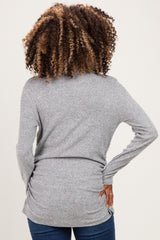 woman wearing a gray maternity sweater with a fitted silhouette, showing the back view and styled with loose curls
