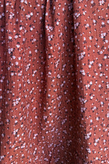 rust floral print fabric with small pink and white flowers on a textured background