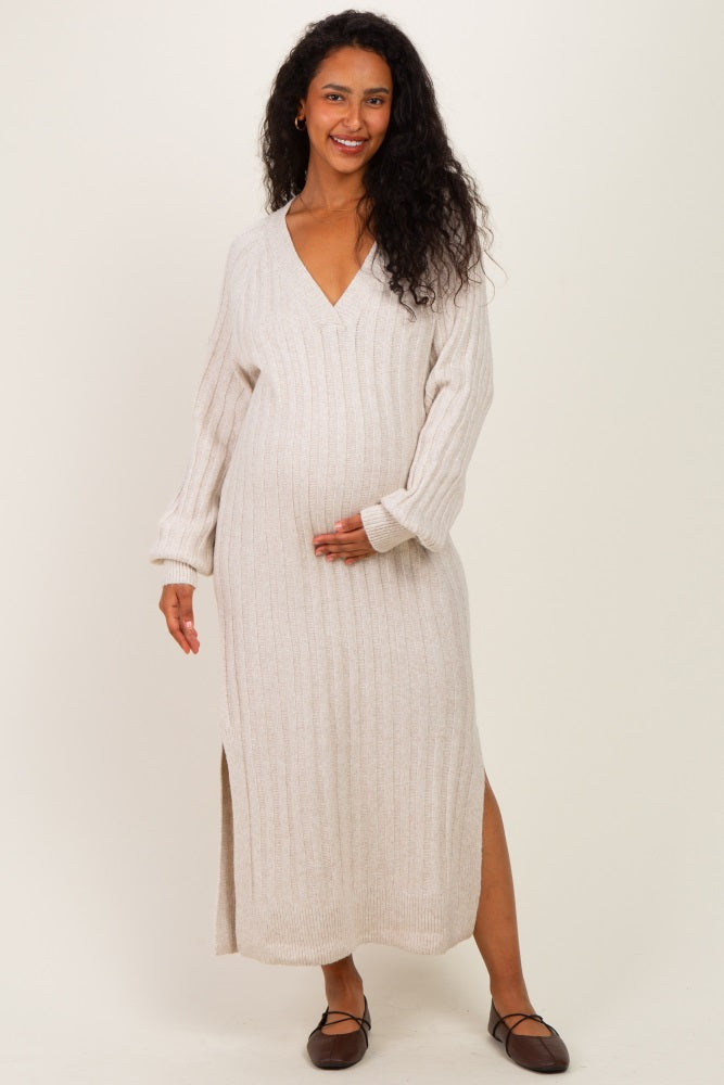 woman wearing a beige long sleeve knitted maternity dress with a v-neck and side slit, showing her baby bump