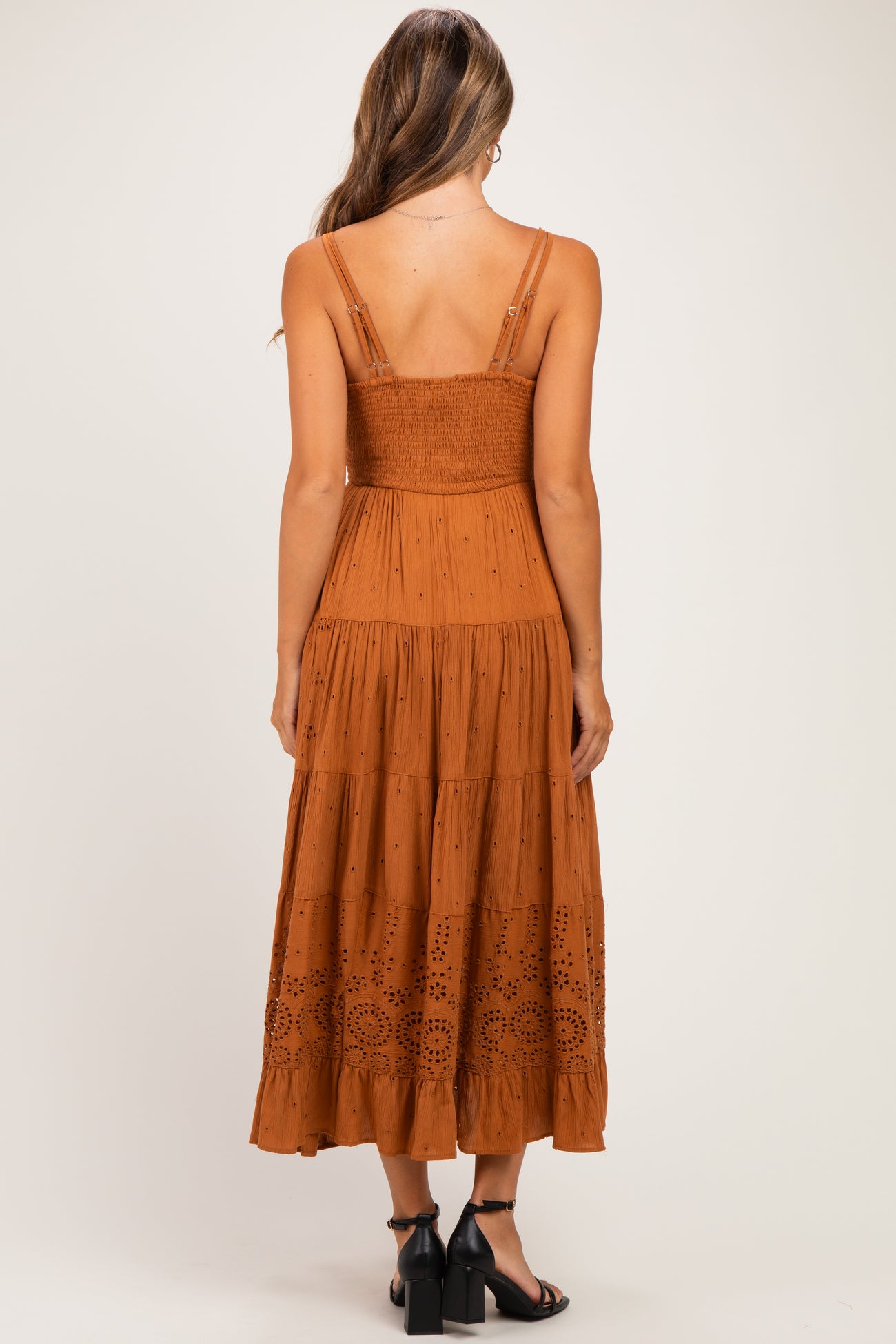 woman wearing a rust brown maternity maxi dress with a smocked bodice and embroidered detailing
