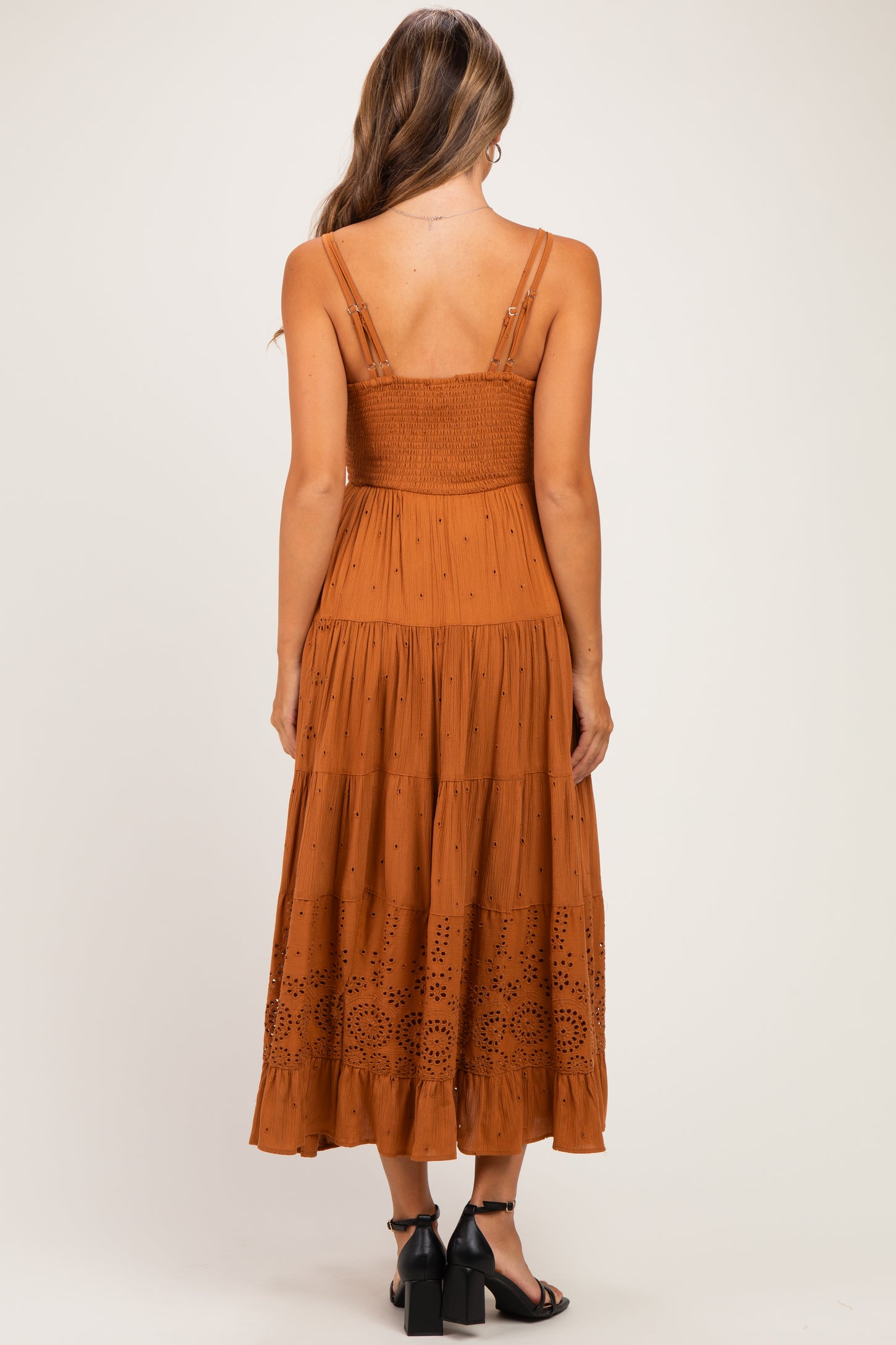 woman wearing a rust brown maternity maxi dress with a smocked bodice and embroidered detailing