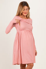 woman wearing a pink striped maternity dress with a crossover front and a visible baby bump