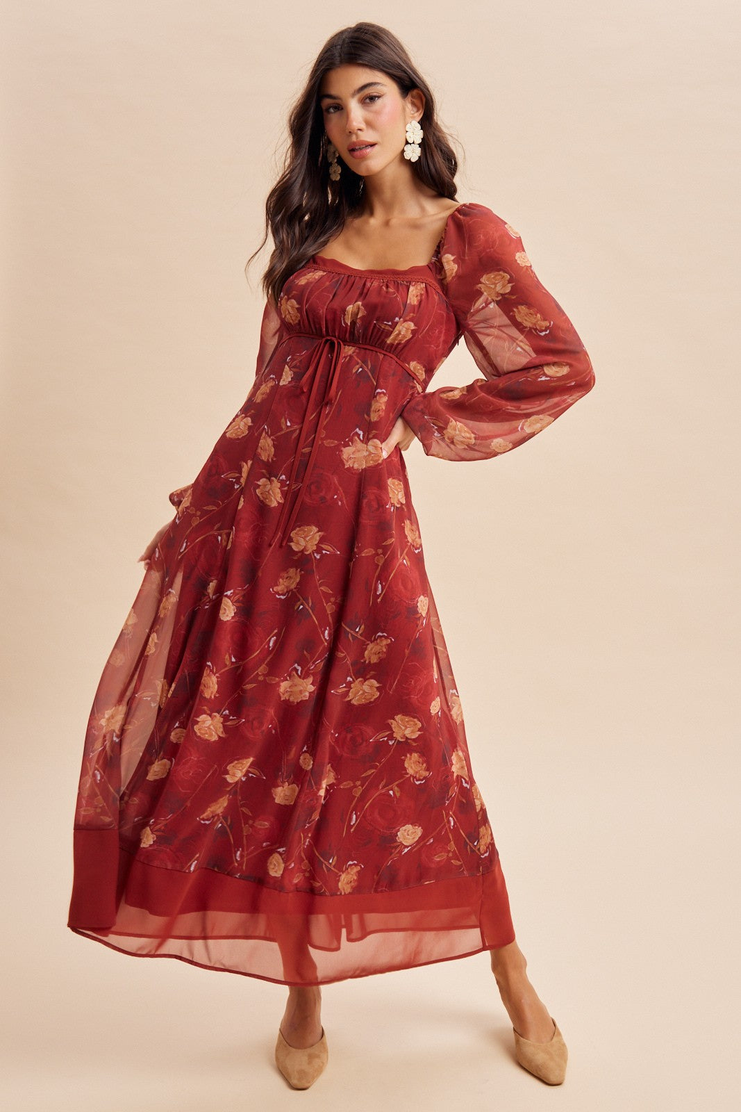 woman wearing a burgundy floral maxi dress with sheer sleeves and a cinched waist, styled with beige heels
