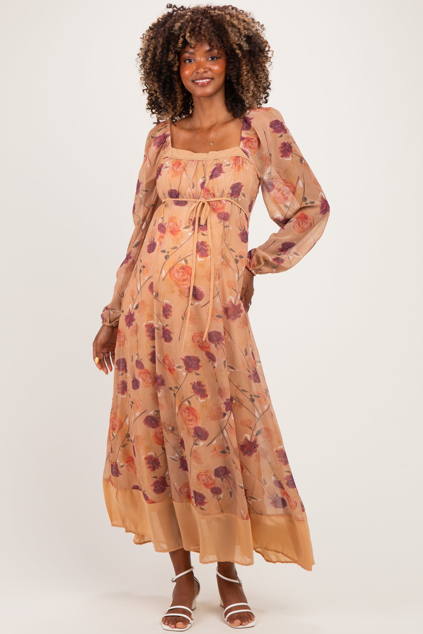 woman wearing a floral print maternity maxi dress with long sleeves and a tie waist, showcasing her baby bump