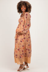 woman wearing a floral maternity maxi dress with long sleeves and a tied waist, holding her baby bump
