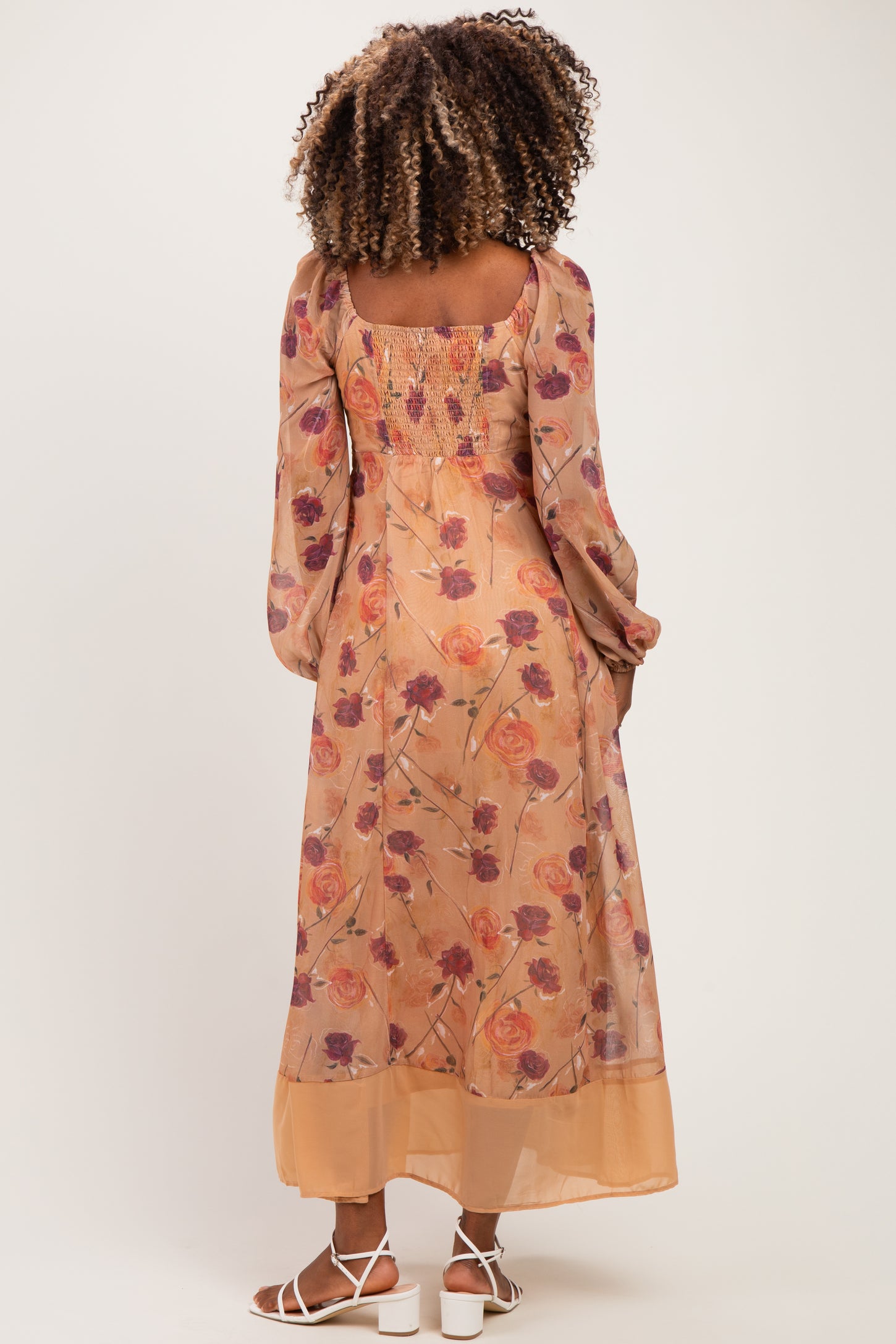 woman wearing a floral maternity maxi dress with smocked bodice and long sleeves, showing a baby bump from the back