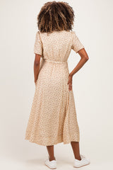 woman wearing a beige floral maternity dress with short sleeves and a waist tie, showing her back
