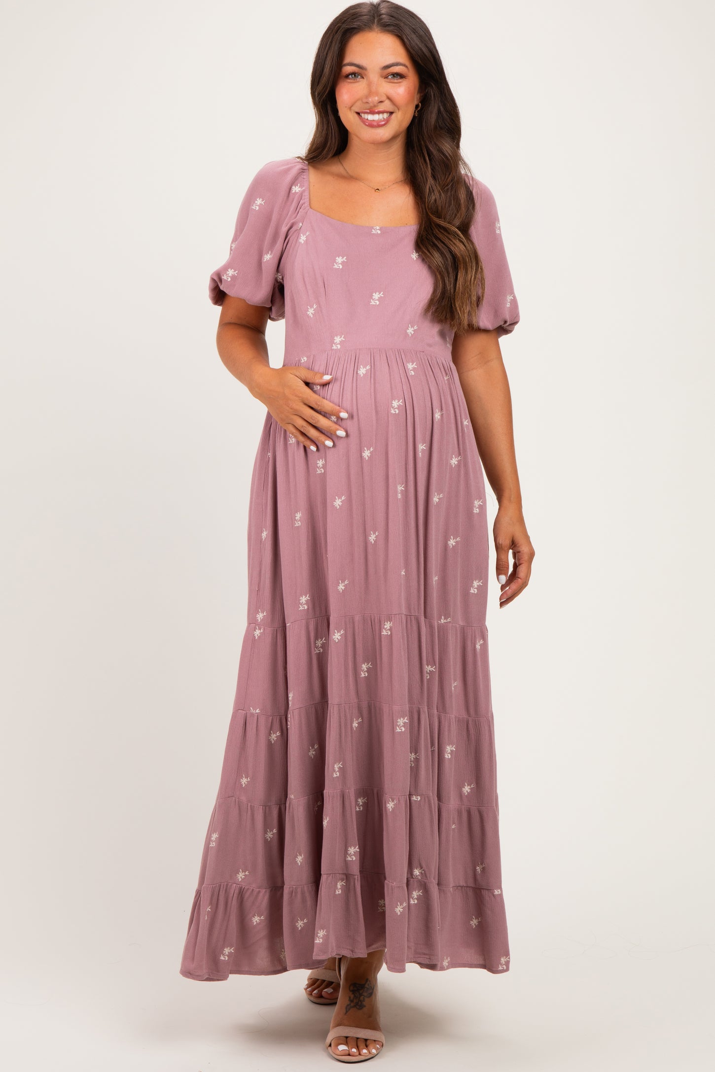 woman wearing a dusty rose maternity maxi dress with puff sleeves and floral details, showing her baby bump