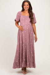 woman wearing a dusty rose maternity maxi dress with puff sleeves and floral details, showing her baby bump