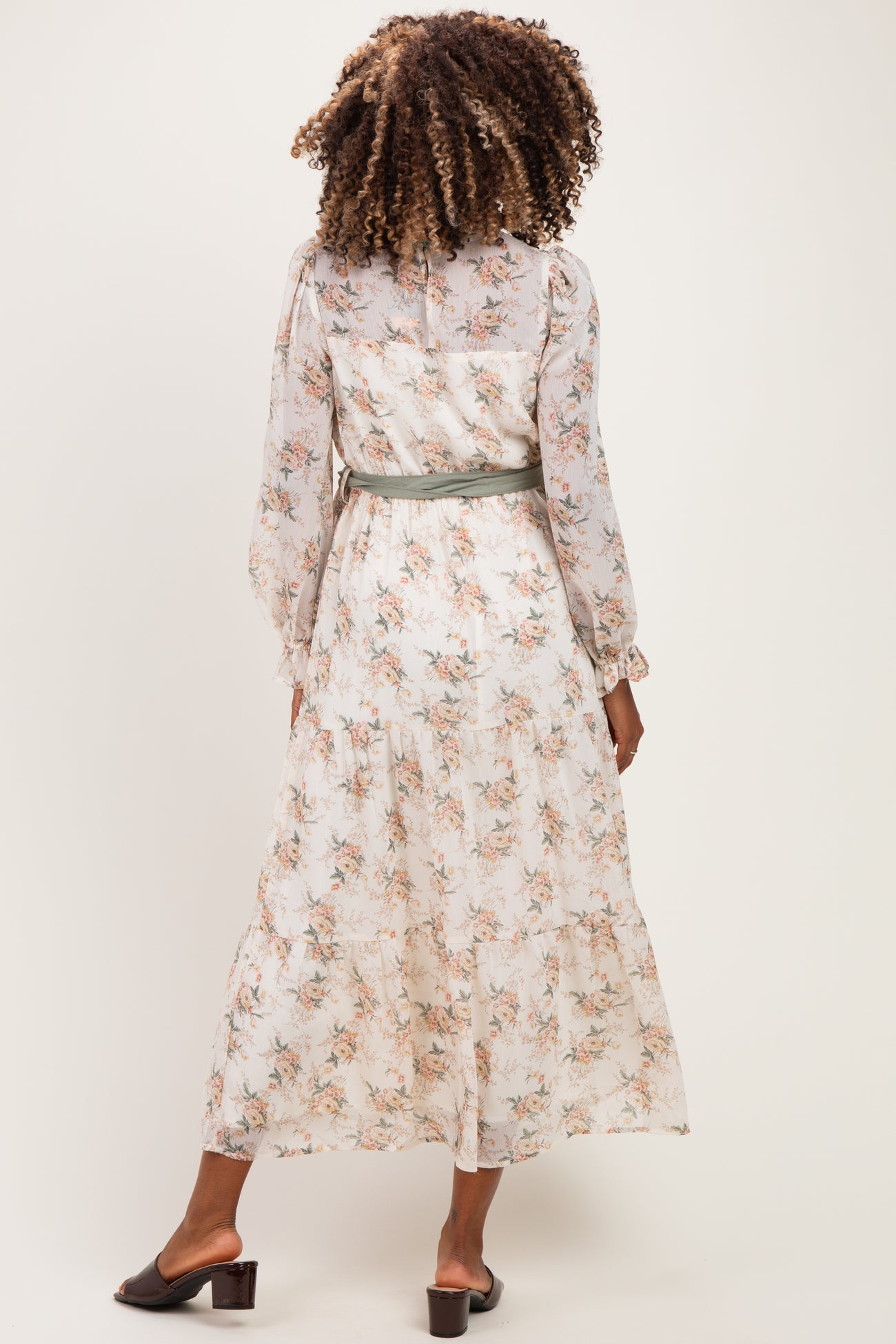 woman wearing a cream floral maternity maxi dress with long sleeves and a tie at the waist