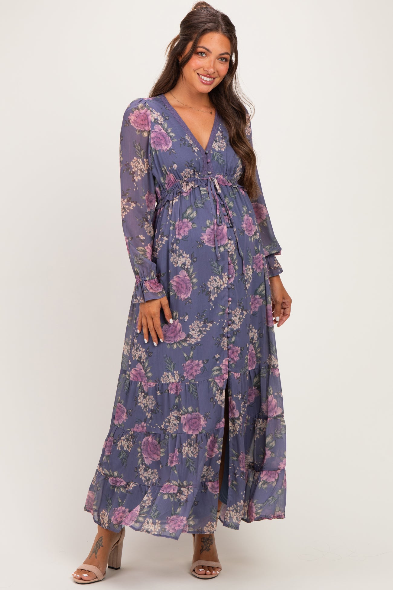 woman wearing a purple floral maternity maxi dress with long sleeves and a cinched waist, showcasing a baby bump