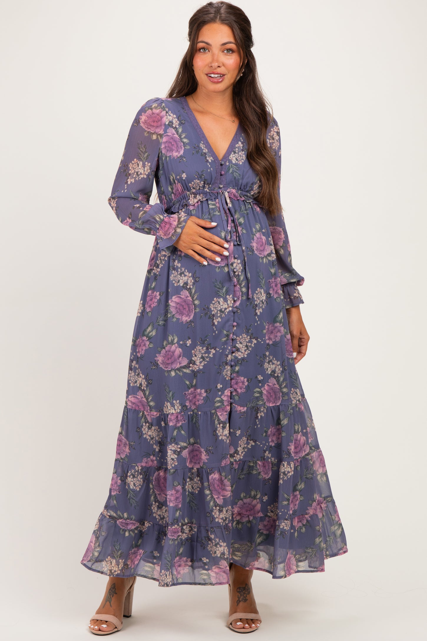woman wearing a purple floral long sleeve maternity dress and holding her baby bump