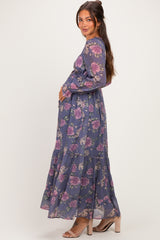 woman wearing a purple floral long sleeve maternity dress, showing her baby bump and styled with a tiered skirt