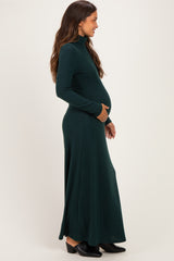 woman wearing a dark green long sleeve maternity dress with a fitted turtleneck and baby bump visible