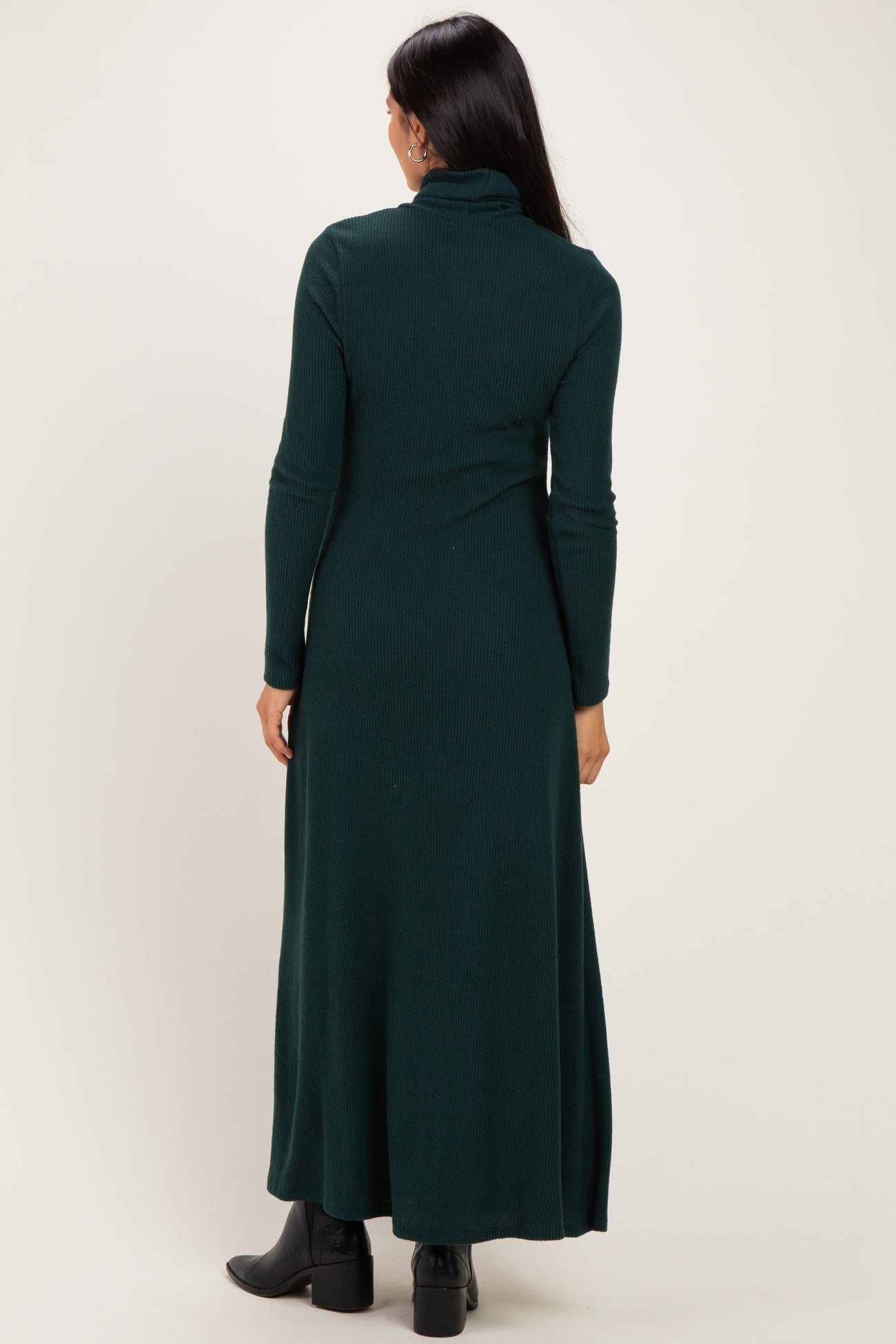 woman wearing a dark green ribbed maxi dress with a high neckline and long sleeves, shown from the back