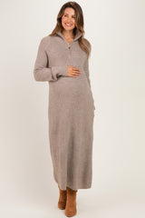 woman wearing a beige long sleeve maternity sweater dress and holding her baby bump
