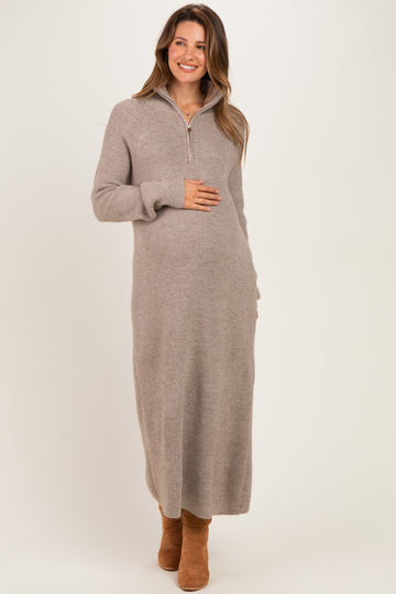 woman wearing a beige long sleeve maternity sweater dress and holding her baby bump