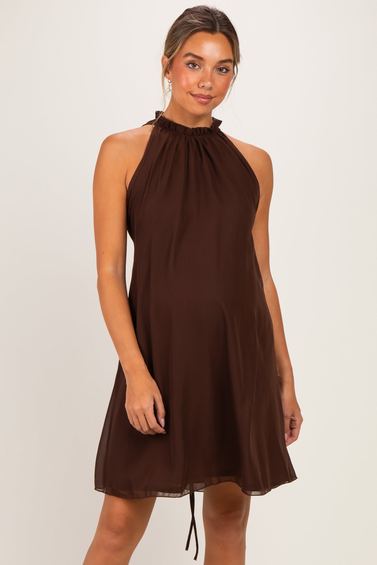 woman wearing a chocolate brown halter neck maternity dress with a baby bump visible