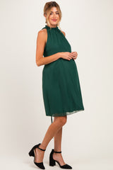 woman wearing a dark green halter neck maternity dress with a flowy silhouette and visible baby bump
