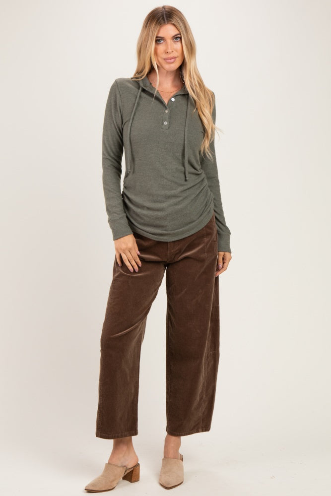 woman wearing an olive green long sleeve hooded henley top with buttons and brown wide leg corduroy pants