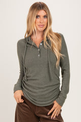 woman wearing a dark green long sleeve hooded henley top with buttons and a relaxed fit