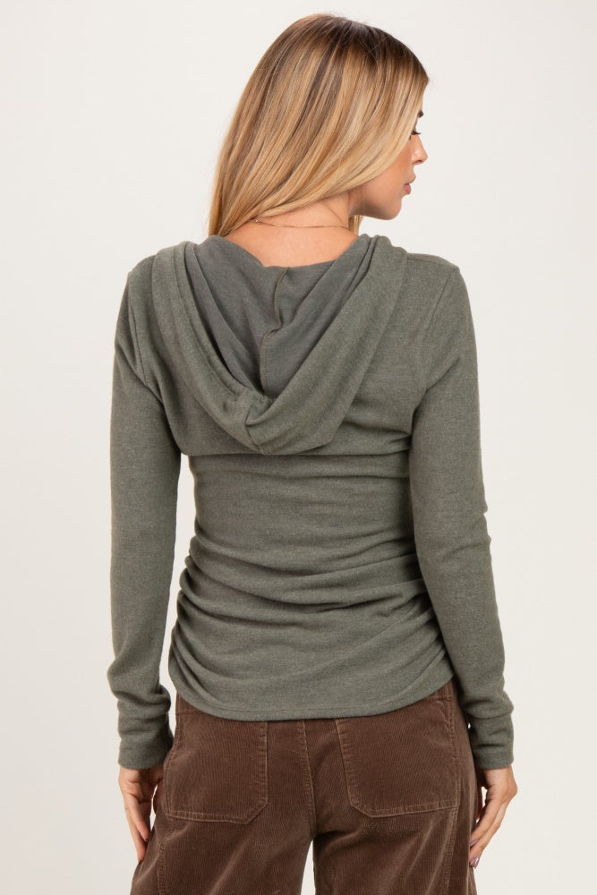 woman wearing an olive green long sleeve hooded top, showing the back view and styled with brown corduroy pants