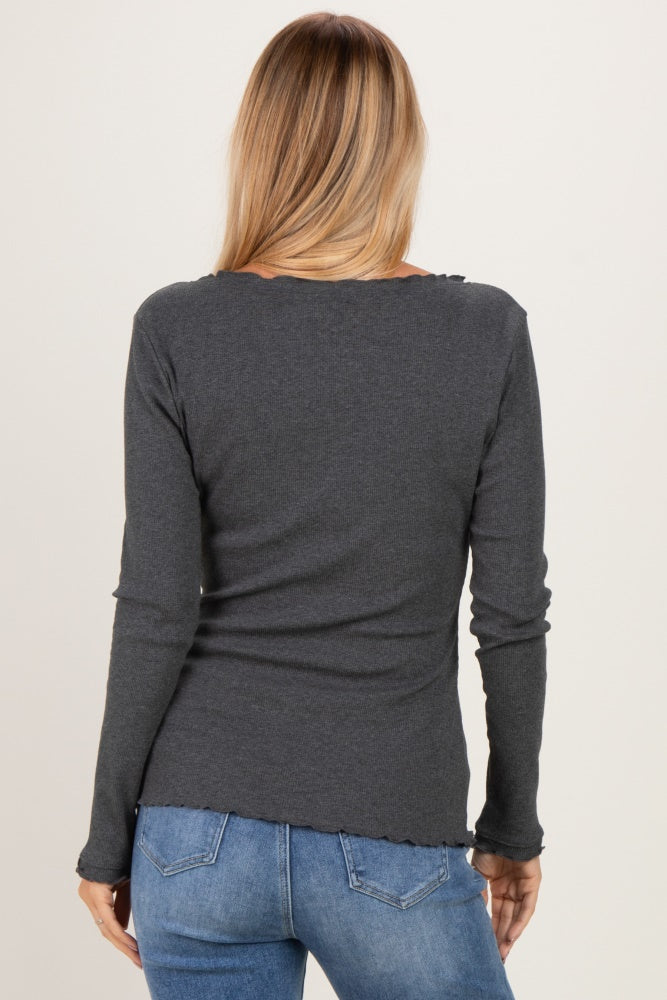 woman wearing a dark gray long sleeve top with a ruffled hem and back view, paired with blue jeans