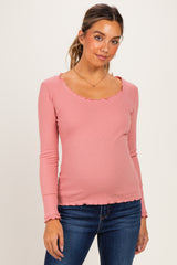 woman wearing a pink long sleeve maternity top with ruffle details and a visible baby bump