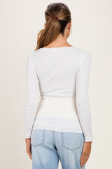 woman wearing a white long sleeve maternity top, viewed from the back with light blue jeans