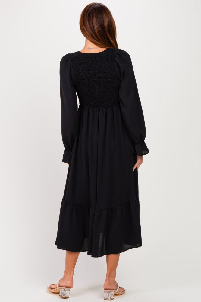 woman wearing a black long sleeve midi dress with a smocked bodice and ruffled hem, shown from the back